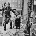 Vojak Conrad Schumann preskakuje zátarasy zo sovietskeho sektoru Berlína do západného pred dokončením stavby Berlínskemu múru.