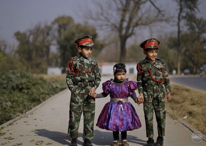 Pakistan - Dvaja bratia oblečení vo vojenskom oblečení vedú svoju sestru cez cestu do photo štúdia kde sa budú fotiť na rodinný portrét.